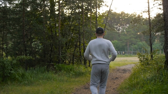 Young Sports Man In The Baseball Cap Runs Through The Woods