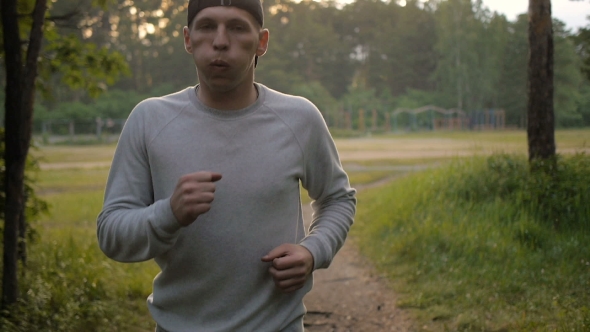 Young Sports Man In The Baseball Cap Runs Through The Woods