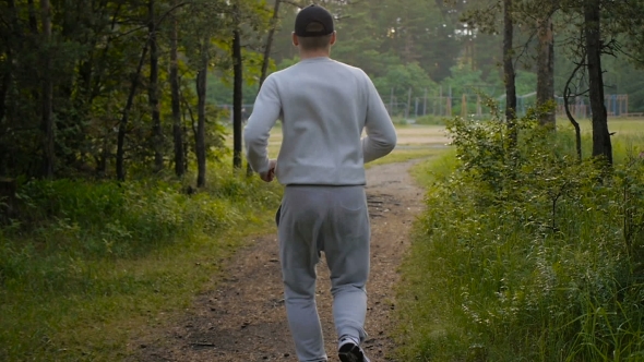 Young Sports Man In The Baseball Cap Runs Through The Woods