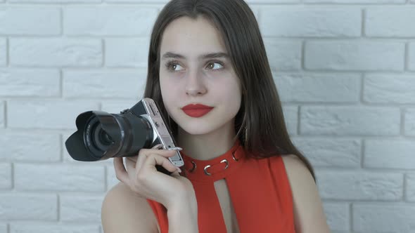 A beautiful girl holds a camera in her hands. alt