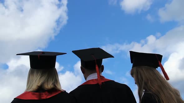 Happy Future of Graduates, Three Students Throwing Academic Caps Up in the Air alt