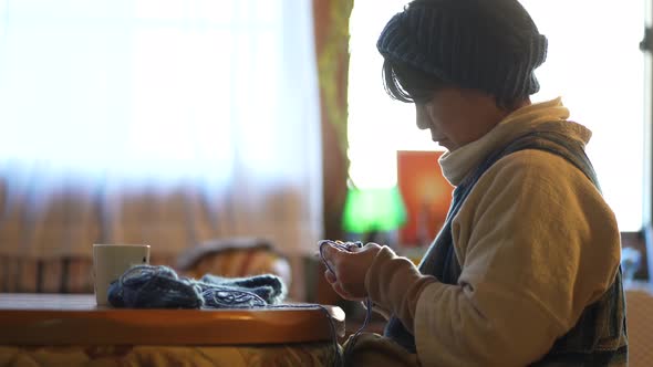 A woman knitting a neck warmer alt