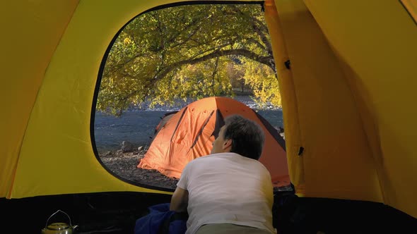 Back View of Adult Traveler in White T-shirt Looks from Open Tent, Altai alt