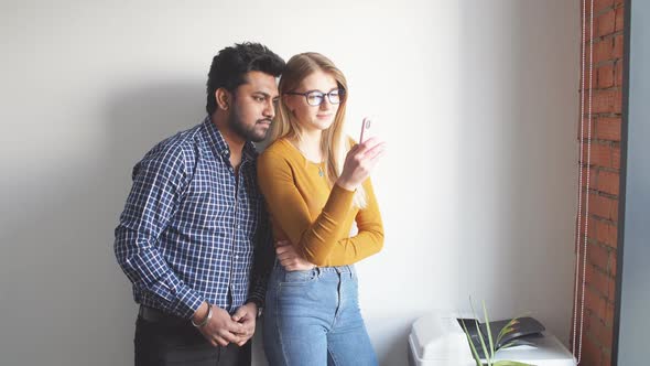 Happy Mix-race Couple Holding Digi While Standing and Celebrating Isolated Over Gray Wall Background alt