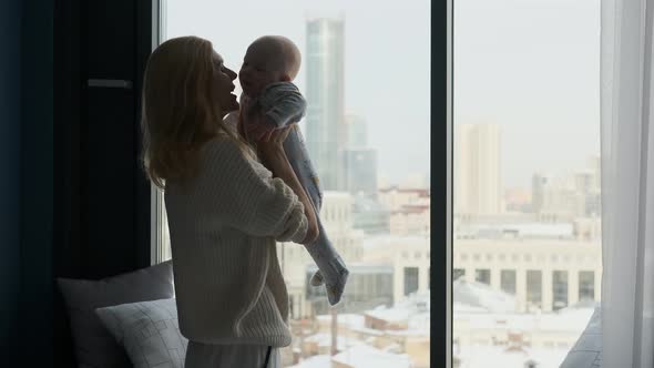 silhouette woman playing with toddler standing by the window