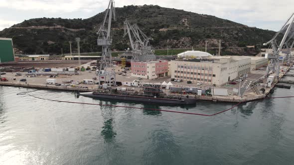 Navy submarine moored to quay of Cartagena industrial port, Spain. Aerial approach