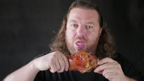 Man Biting With Relish A Piece Of Pork Knuckle