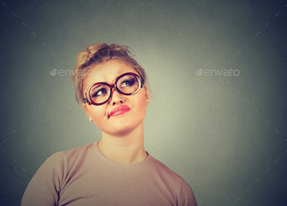 confused skeptical woman in glasses thinking planning looking up