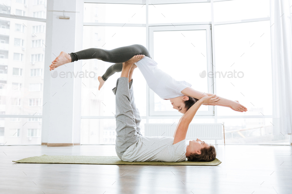 Man and Woman Doing Acro Yoga or Pair Yoga Indoor Stock Photo