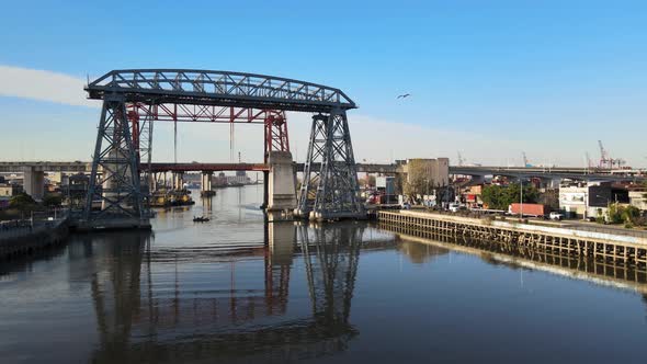 Aerial pan Puente Transbordador and small boat on river, Buenos Aires alt