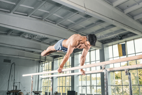 Male gymnast performing handstand on parallel bars