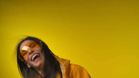 A Young Cheerful Woman in a Yellow Raincoat is Happy to Hold an Axe in Her Hand alt