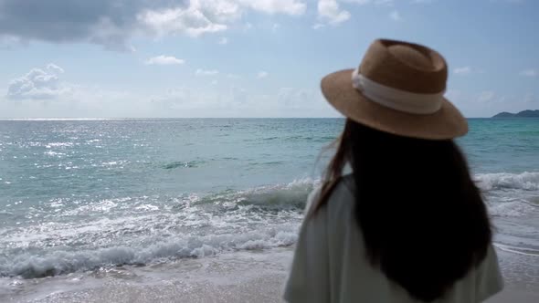 Slow motion rear view blurred of a woman with hat standing and looking at the sea