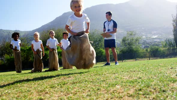 Children playing a sack race in park alt