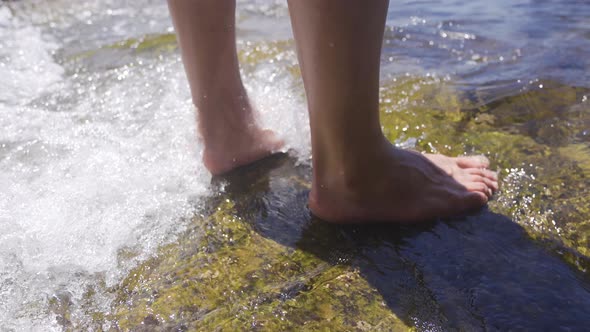Bare feet touch the sea water. alt