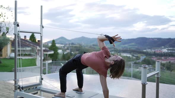Man doing yoga in Wheel pose on pilates reformer alt