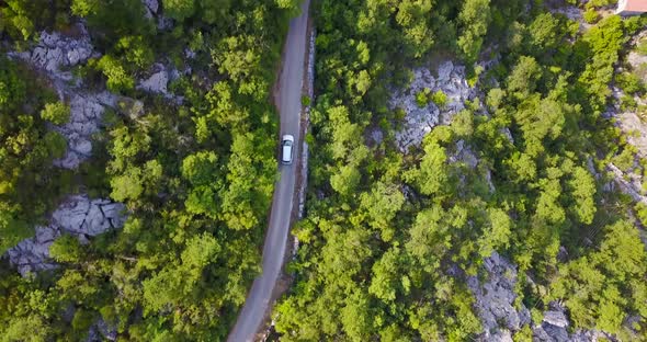 Aerial drone view of a minivan car vehicle driving on a rural road alt