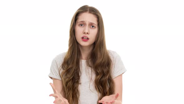 Indoor Portrait of Displeased Teenager Woman in Casual Tshirt Gesturing Hands in Irritating Manner alt