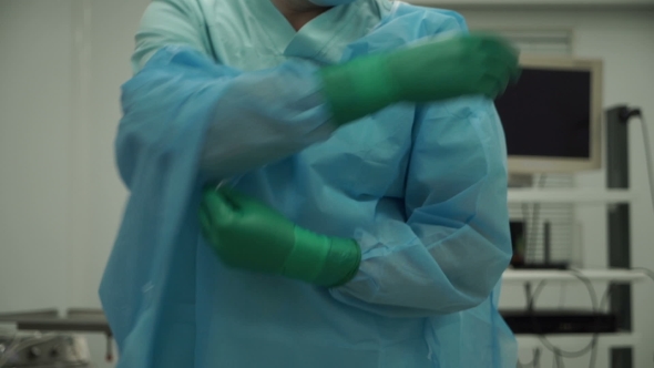 Male Surgeon Removes Gloves And Gown After Surgery
