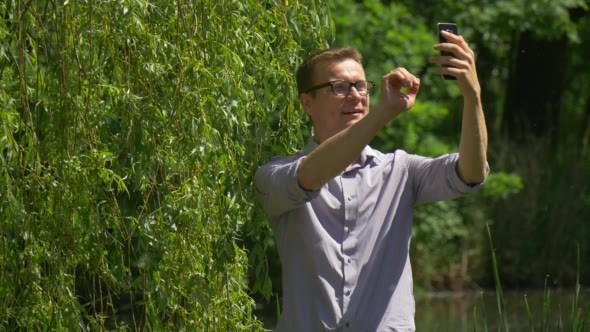 Man Makes Video Call on Mobile Phone in Park