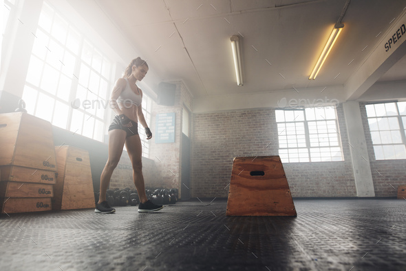 Muscular young woman working out with a box at crossfit gym