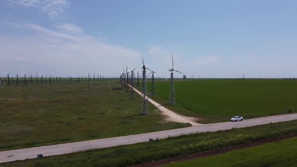 Tall White Wind Farms Stand By Among the Bright Green Beautiful Fields