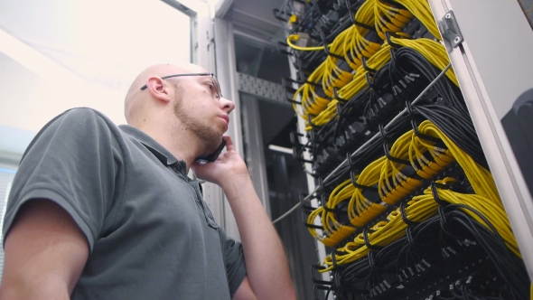 IT Engineer Talking On The Phone And Plug In Cable alt