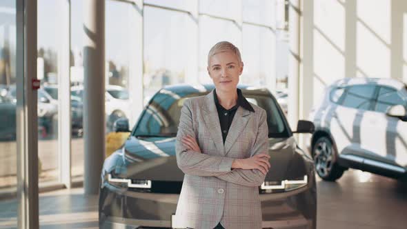 Close Up of Woman Inside Car Dealership While Standing in Front of Shiny New alt