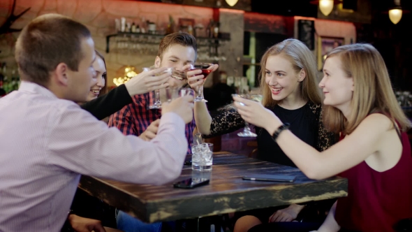 Company Of Young Friends Is Clinking Glasses In The Bar alt