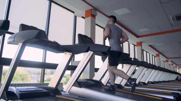 Young Male Athlete Running On Treadmill In The Gym