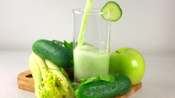 Pouring Green Smoothy In a Glass. Apple, Cucumber And Celery. alt