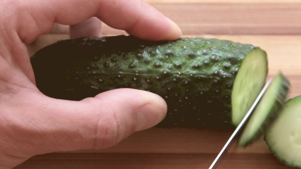 Sliced Fresh Cucumber On a Wooden Board With a Knife