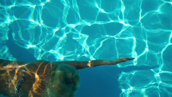 Young Woman Swimming Under Water In The Swimming Pool