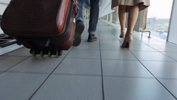 Couple Of People Walks Through Airport Carrying Luggage With Them ...