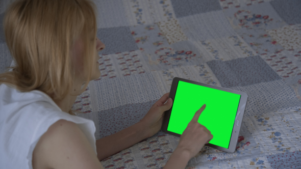 Beautiful Girl Using Tablet PC with Pre-keyed Green Screen Lying on Bed at Home 3 alt