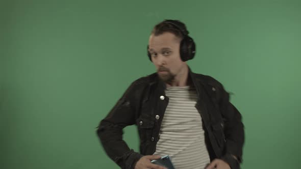 Young Handsome Man with Headphones Dancing on the Background of a Green Screen alt