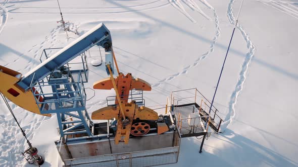 Aerial View of Pumpjack on Oil Well in Snowy Field in Winter Day alt