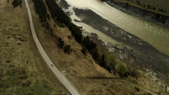 A White Car Drives Along a Mountainous Asphalt Road alt