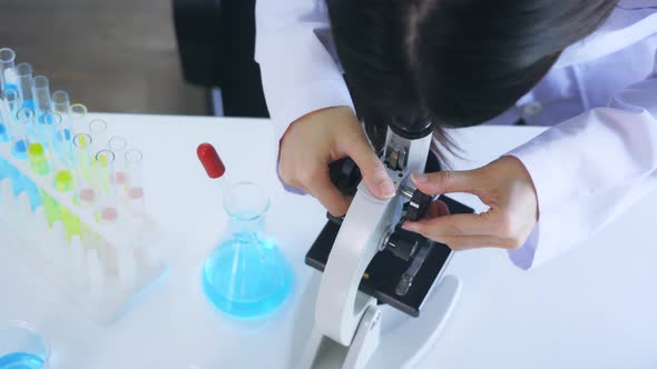 Scientist in Medical Labcoat Performing Research in Lab While Seeing Elements Through Microscope alt