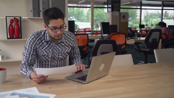 Man Working With Financial Diagrams In Empty Startup Office. alt