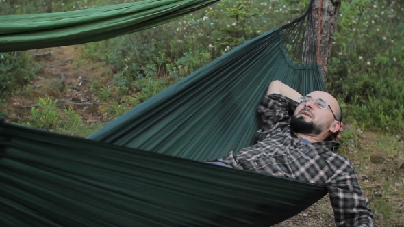 Man Relaxing in Hammock in the Summer Green Forest