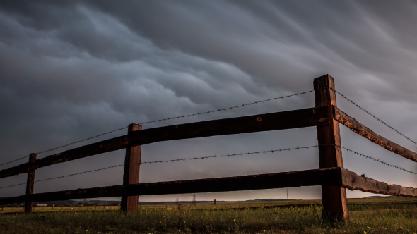 Fence in the Field Under Stormy Cloud Sky