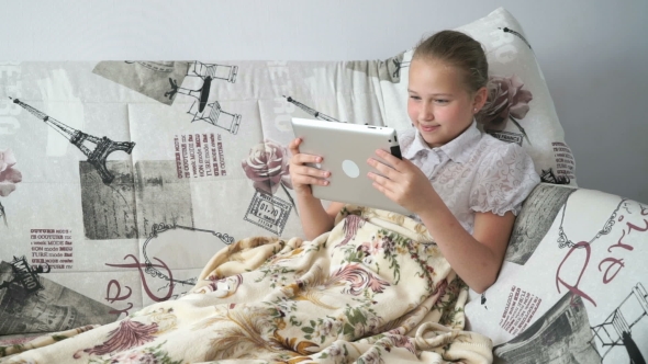 Child Reading a Digital Tablet Lying On The Bed