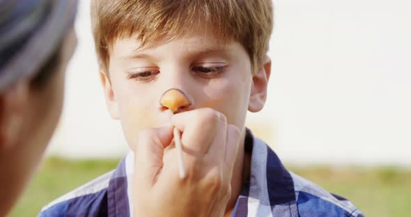 Woman applying paint on boy nose 4k alt
