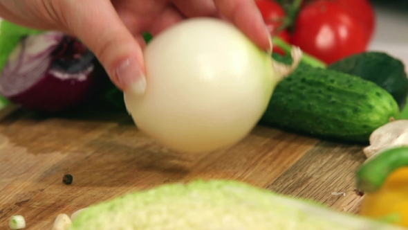 Female Hands Cut Onion Into Two Parts.