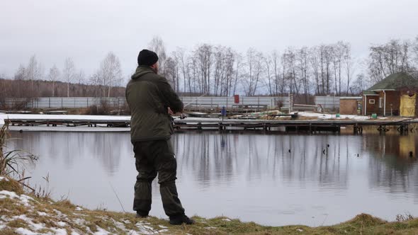 Unrecognizable Man Fishing in Lake at Dawn