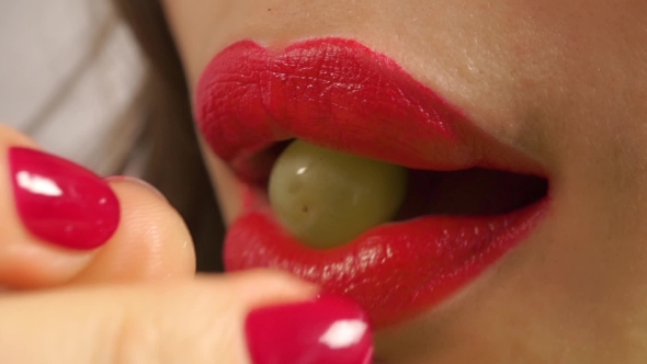 Young Woman With Red Manicure And Red Lips Eating Green Grape alt