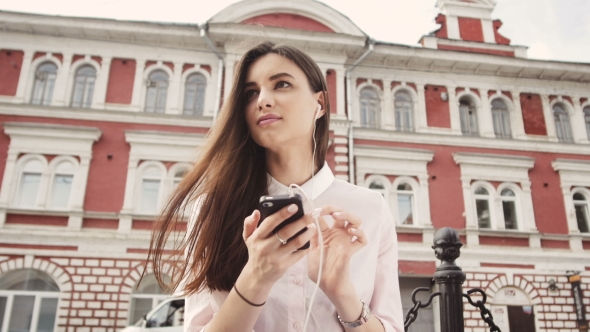 Smiling Urban Girl Uses Smart Phone With Smile On Her Face alt