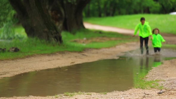 Cute Girl And Boy Running In Huge Puddle
