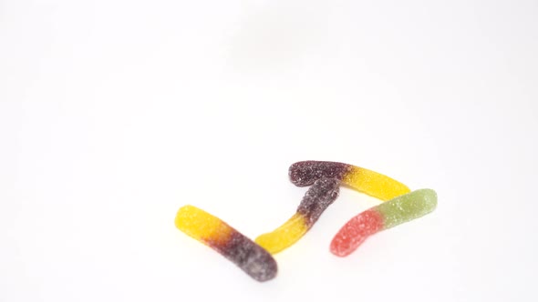 Jelly Worms Macaroons and Milk Chocolate Dropping on the Table Sweets Assortment alt